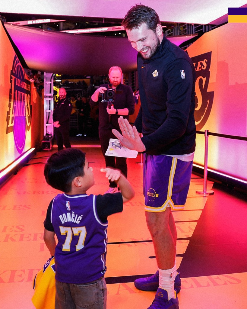 Basketball player Luka Doncic high-fives a child wearing his jersey.