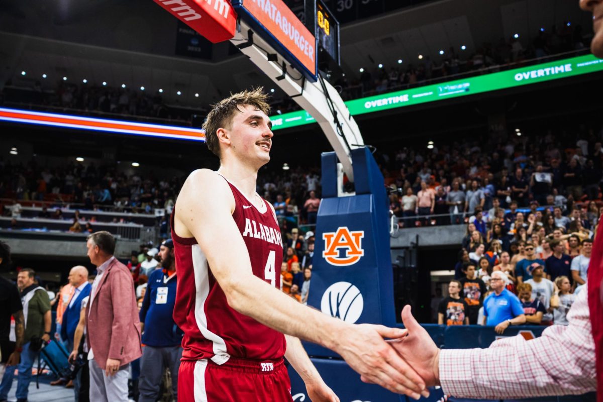 Alabama forward Grant Nelson high-fives fans after beating Auburn at Neville Arena in Auburn, AL, on March 8, 2025.