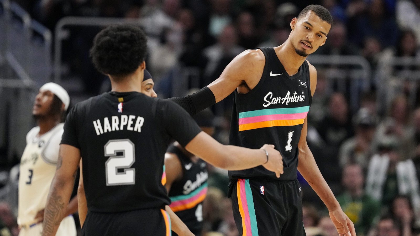 Spurs forward Victor Wembanyama (1) and guard Dylan Harper (2) shake hands during the fourth quarter against the Milwaukee Bucks at Fiserv Forum