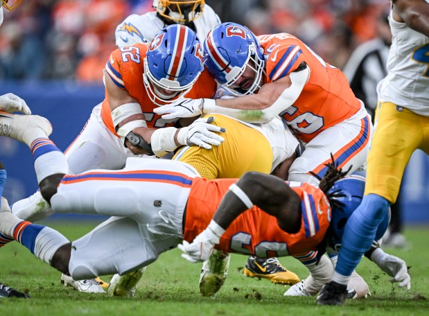 Jonah Elliss (52), Adam Prentice (46) and Jordan Turner (55) of the Denver Broncos team up to stop Jaret Patterson (32) of the Los Angeles Chargers during the third quarter at Empower Field at Mile High in Denver, Colorado on Sunday, Jan. 4, 2026. (Photo by AAron Ontiveroz/The Denver Post)