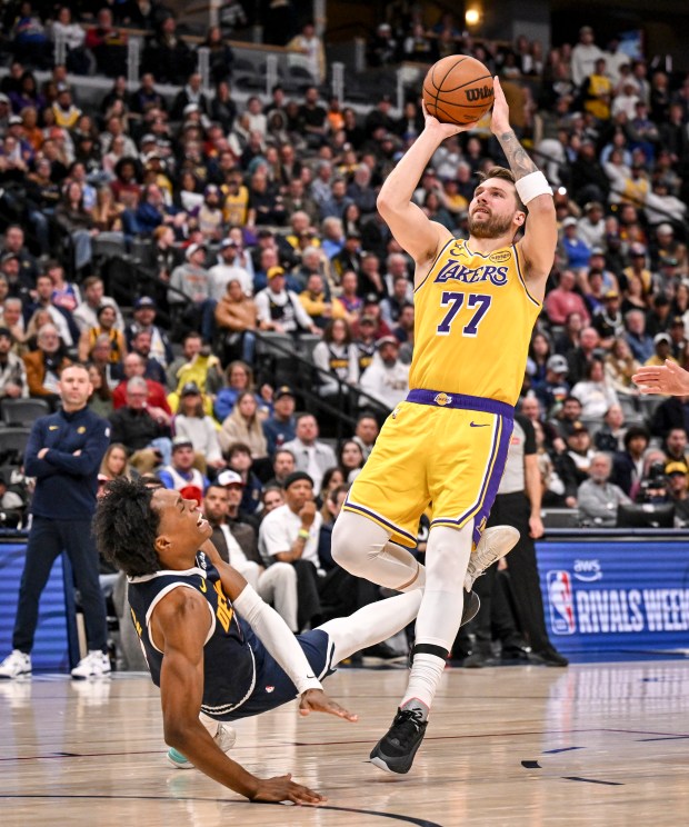 Peyton Watson (8) of the Denver Nuggets draws a charge from Luka Doncic (77) of the Los Angeles Lakers during the fourth quarter of the Lakers' 115-107 win at Ball Arena in Denver, Colorado on Tuesday, January 20, 2026. (Photo by AAron Ontiveroz/The Denver Post)