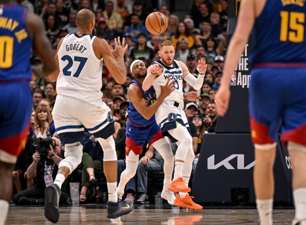 Donte DiVincenzo (0) of the Minnesota Timberwolves passes to Rudy Gobert (27) as Bruce Brown (11) of the Denver Nuggets defends during the fourth quarter of the Timberwolves' 117-108 win at Ball Arena in Denver on Sunday, March 1, 2026. (Photo by AAron Ontiveroz/The Denver Post)
