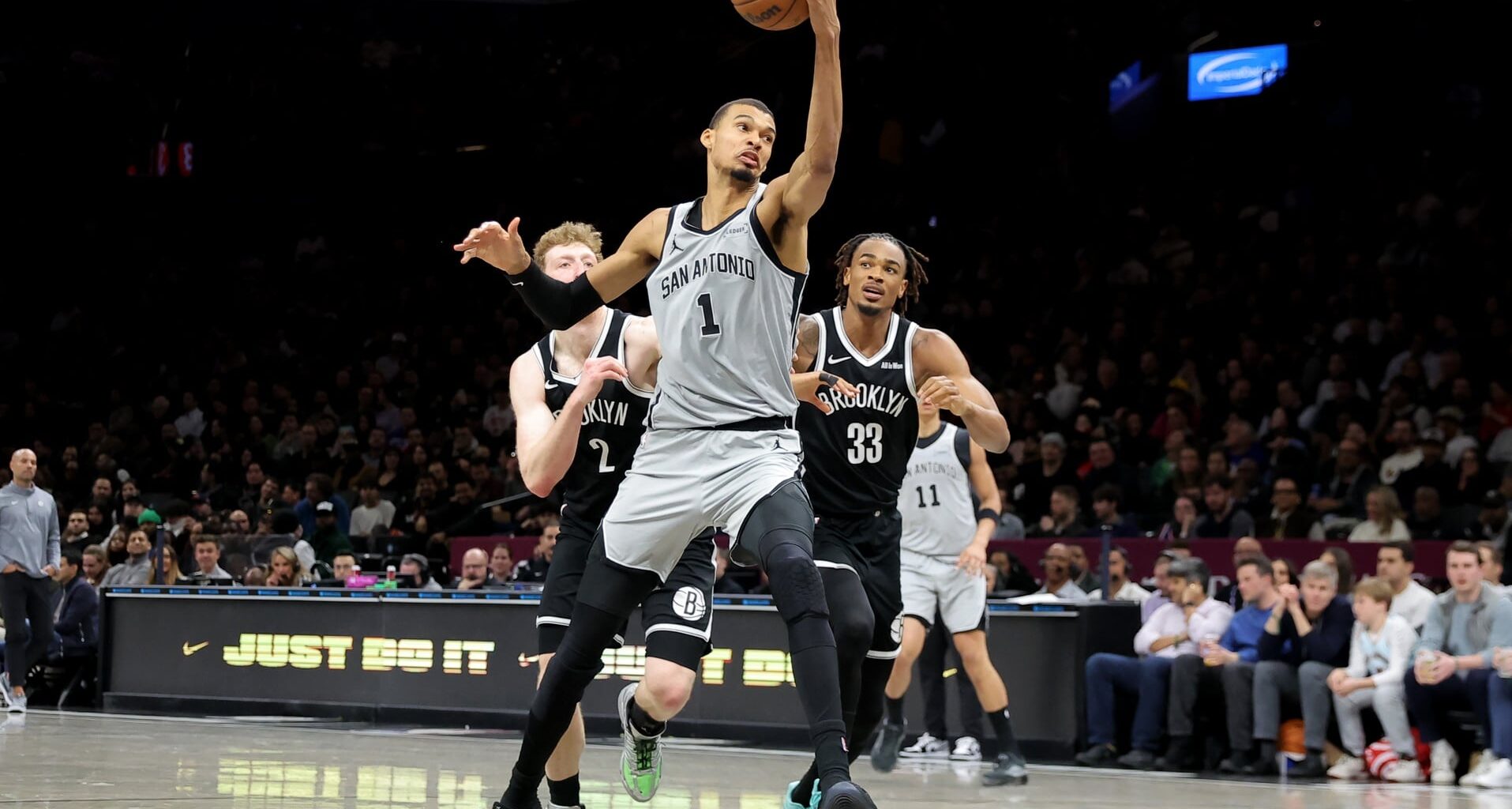 Feb 26, 2026; Brooklyn, New York, USA; San Antonio Spurs forward Victor Wembanyama (1) drives to the basket against Brooklyn Nets forward Danny Wolf (2) and center Nic Claxton (33) during the second quarter at Barclays Center. Mandatory Credit: Brad Penner-Imagn Images