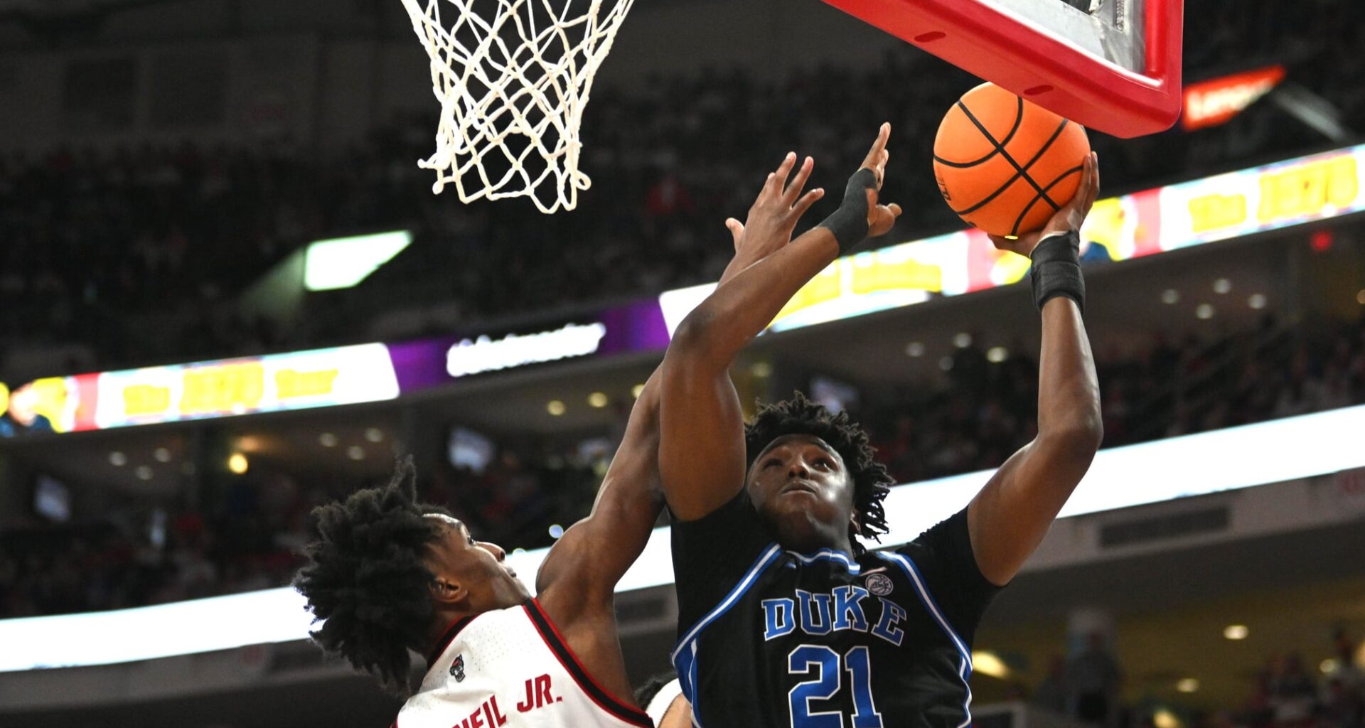 Duke Blue Devils center Patrick Ngongba II (21) lays the ball up against NC State Wolfpack guard Paul McNeil Jr. (2) during the second half at Lenovo Center.