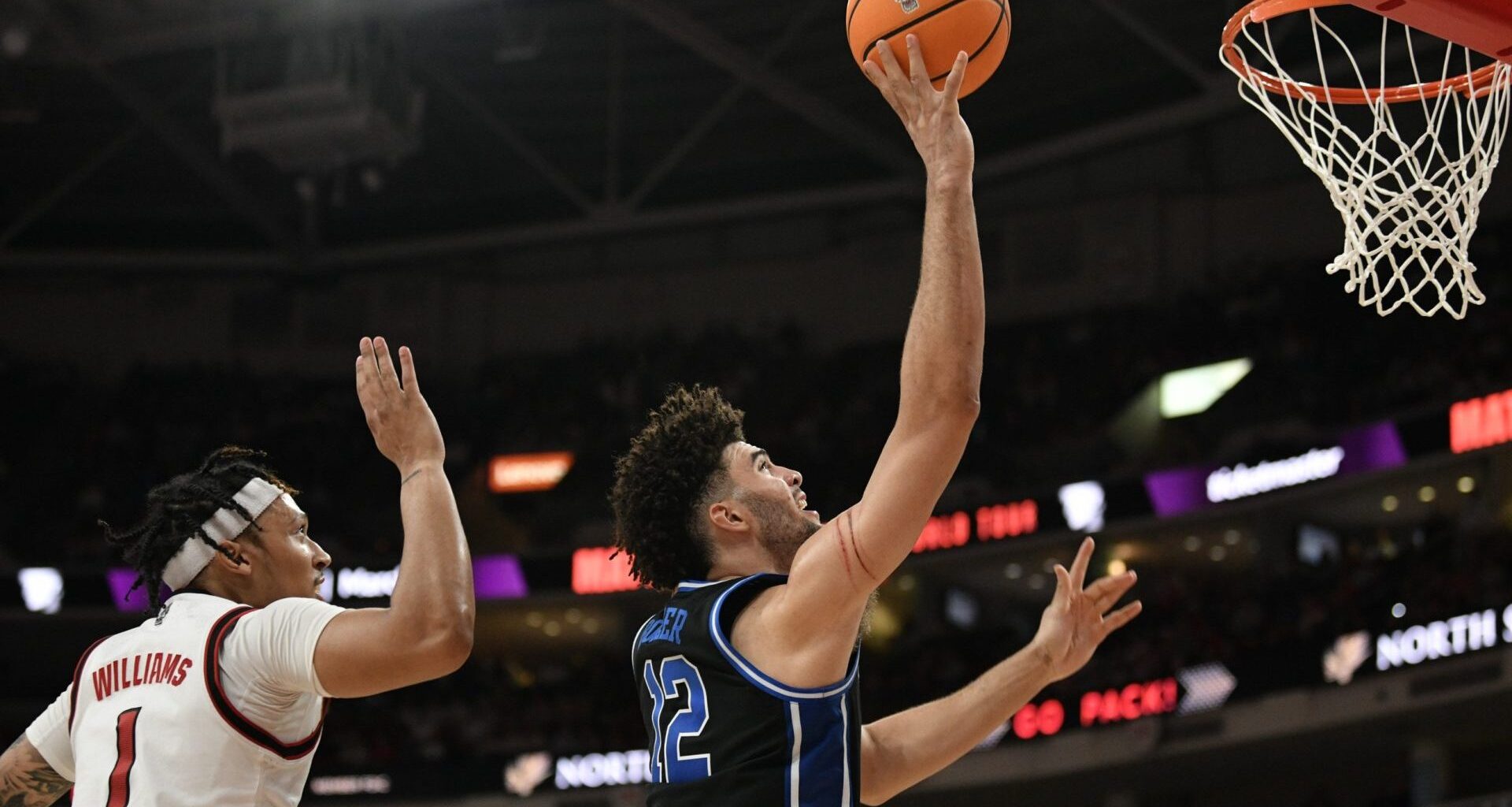 Mar 2, 2026; Raleigh, North Carolina, USA; Duke Blue Devils forward Cameron Boozer (12) lays the ball up against NC State Wolfpack forward Darrion Williams (1) during the second half at Lenovo Center. Mandatory Credit: Zachary Taft-Imagn Images