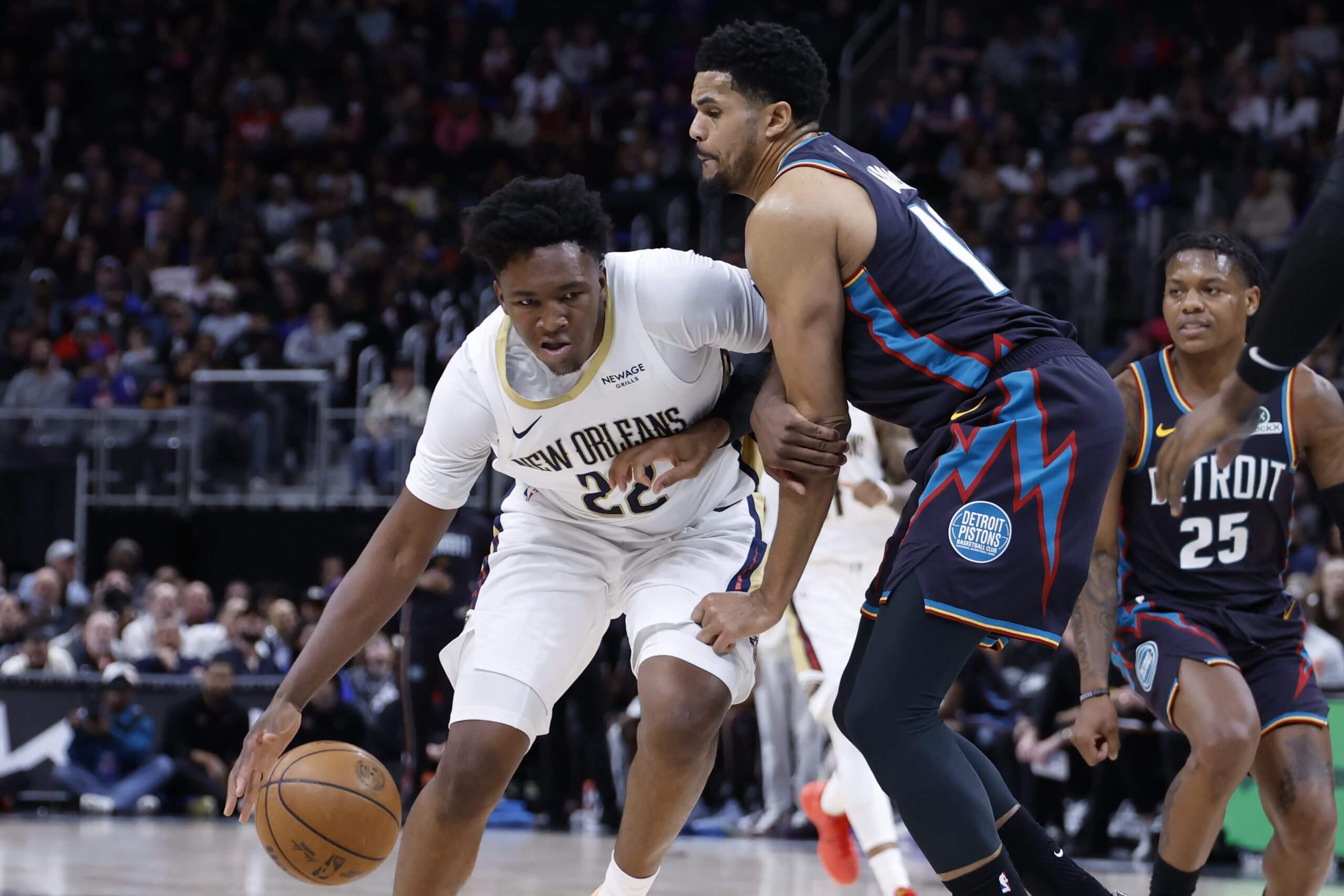 An image of New Orleans Pelicans center Derik Queen dribbling the ball in his right hand with a defender draped all over him.