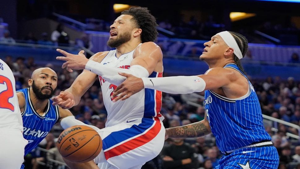 Detroit Pistons guard Cade Cunningham, center, loses control of the ball as he tries to go between Orlando Magic guard Jevon Carter, left, and forward Paolo Banchero during the first half of an NBA basketball game, Sunday, March 1, 2026, in Orlando, Fla. (AP Photo/John Raoux)
