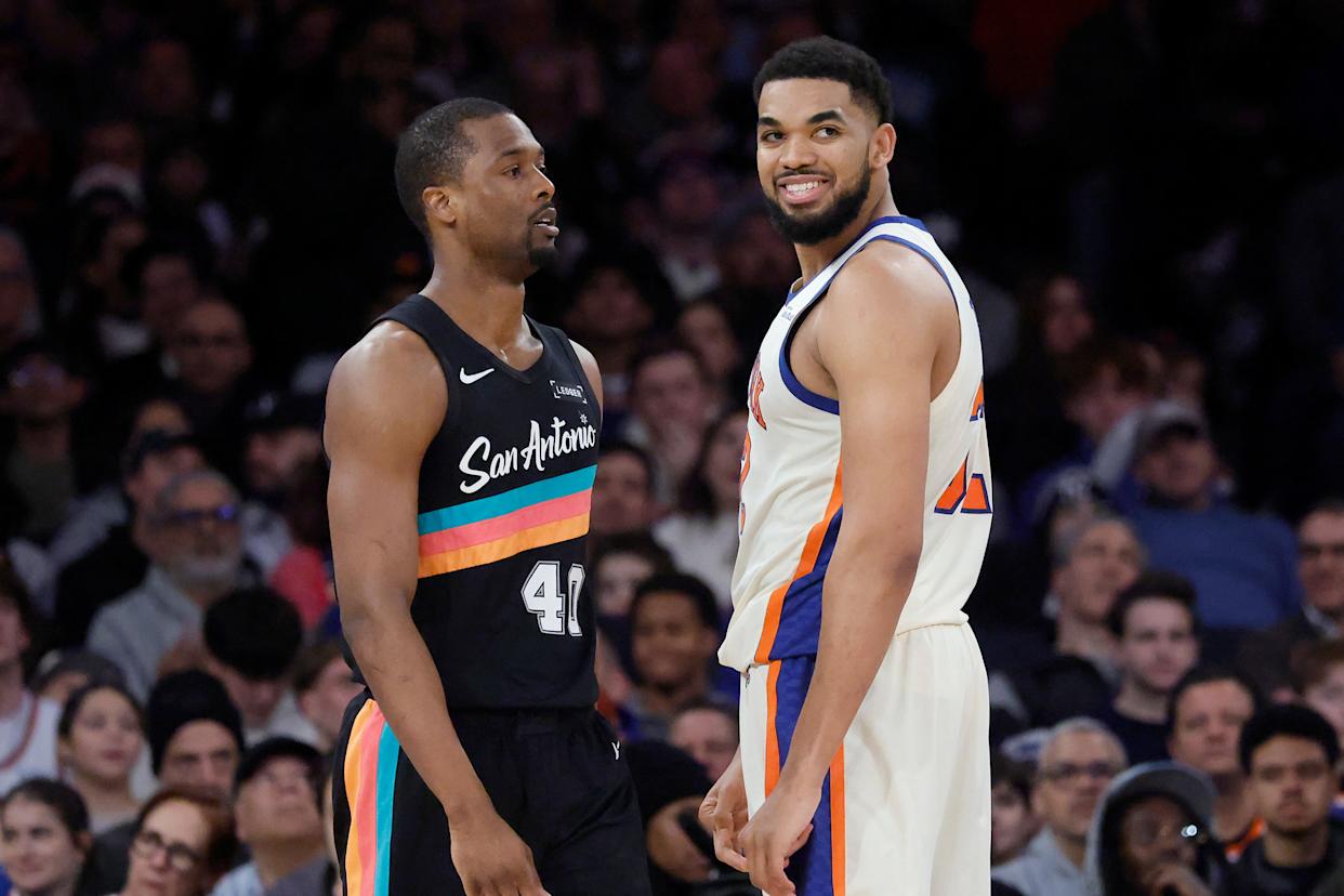 New York Knicks center Karl-Anthony Towns smiling at San Antonio Spurs forward Harrison Barnes.