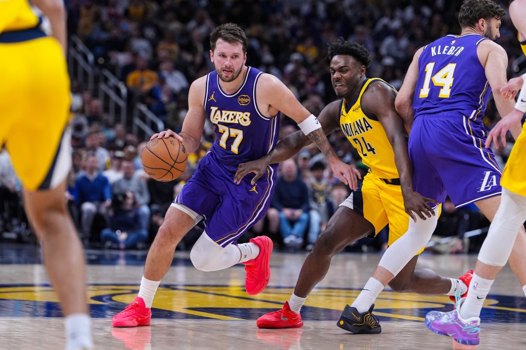 Luka Doncic (77) dribbles past Kobe Brown (24) during an NBA game.