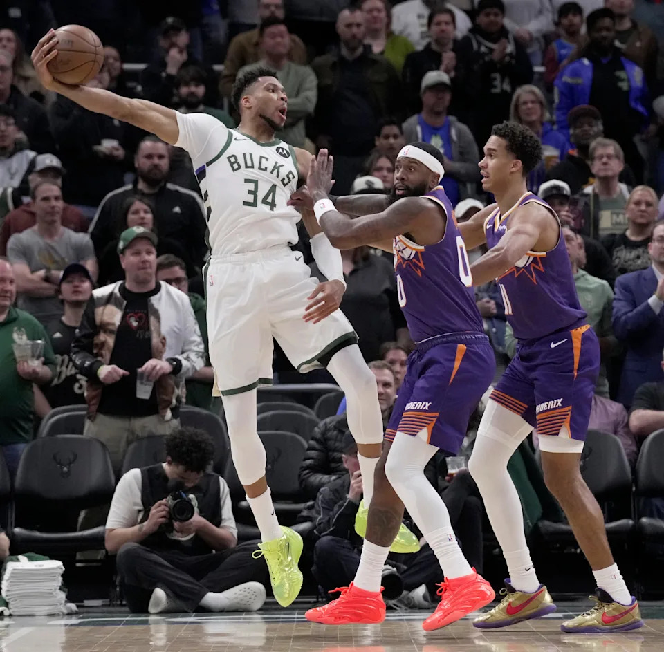 Milwaukee Bucks forward Giannis Antetokounmpo (34) is double-teamed by Phoenix Suns forward Royce O'Neale (00) and forward Oso Ighodaro (11) during the first half of their game Tuesday, March 10, 2026 at Fiserv Forum in Milwaukee, Wisconsin.
