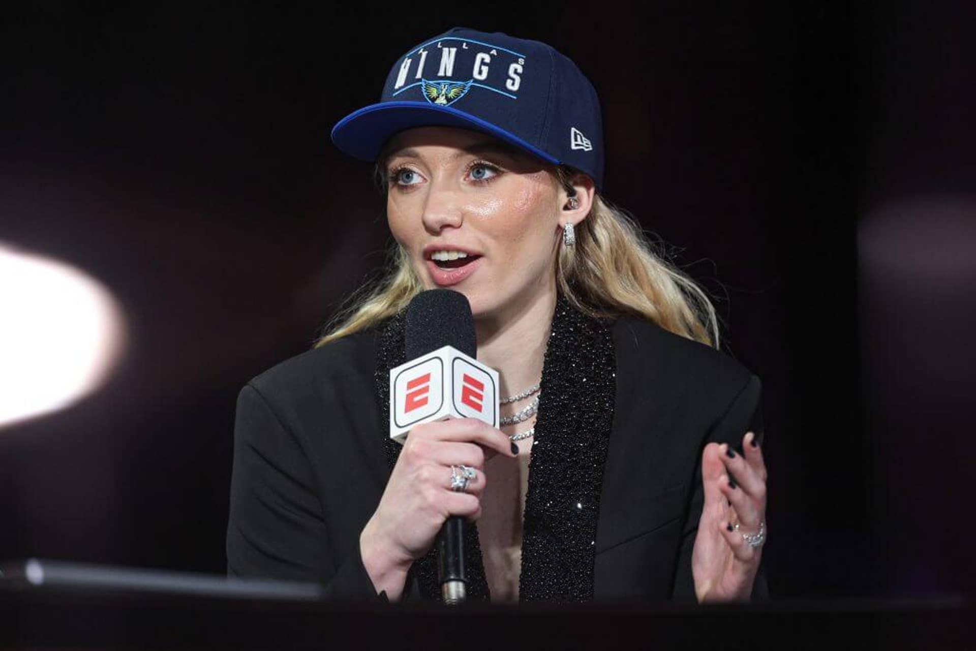 Paige Bueckers, wearing a Dallas Wings ball cap, holds a microphone as she is interviewed after being selected No. 1 by the Wings in the 2025 WNBA Draft.