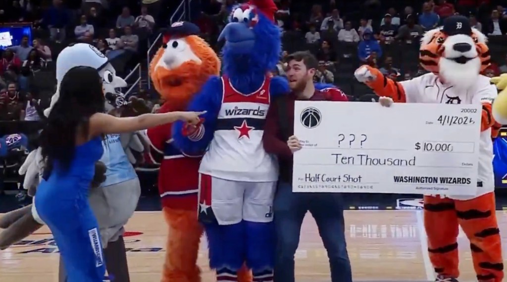 A fan posing for a photo with the Washington Wizards mascots and a fake check for $10,000 for an April Fool's Day prank.