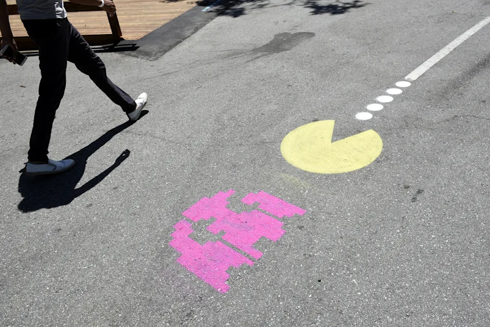 An attendee walks past a Pac-Man logo painted on the ground at the Google I/O Annual Developers Conference in Mountain View, California, U.S., on Wednesday, May 17, 2017. Google's artificial intelligence-based voice Assistant is on more than 100 million devices now, and the company is leveraging a longtime competitor to expand the technology to even more people. Photographer: Michael Short/Bloomberg via Getty Images | Bloomberg via Getty Images