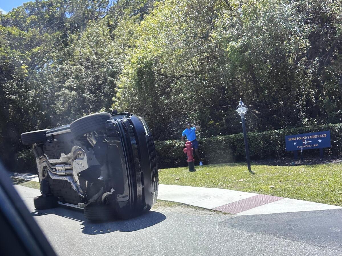 Golfer Tiger Woods stands by his overturned vehicle in Jupiter Island, Fla., March 27.