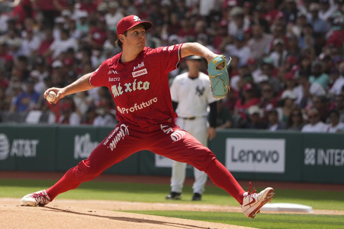 A man in an all-red baseball uniform winds up to pitch