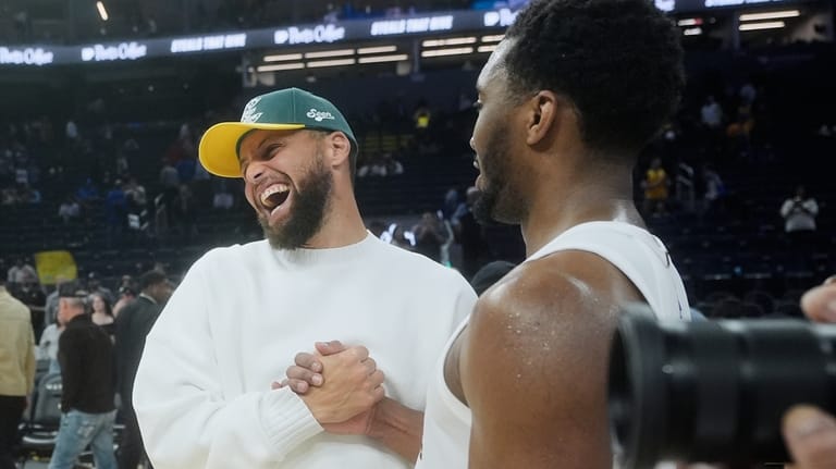 Golden State Warriors guard Stephen Curry, left, smiles while shaking...