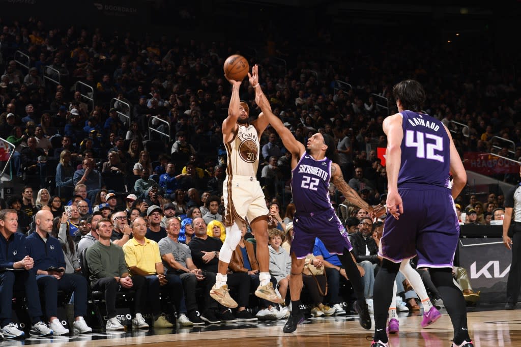 Curry hits a three with a hand in his face. NBAE via Getty Images