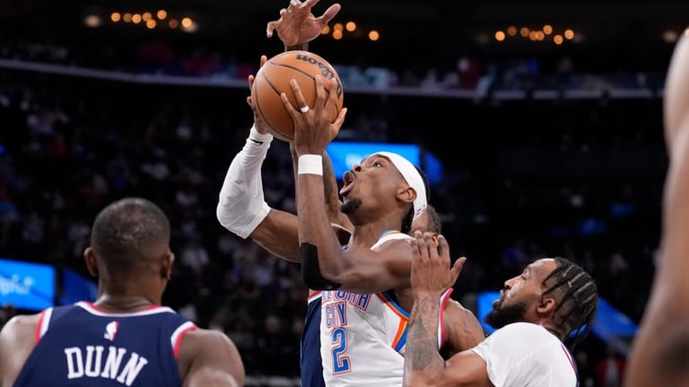 Oklahoma City Thunder guard Shai Gilgeous-Alexander, center, shoots as Los...