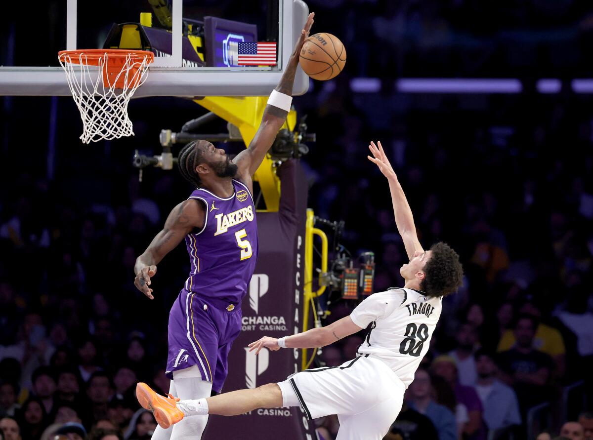Lakers center Deandre Ayton, left, deflects a shot by Nets guard Nolan Traore.