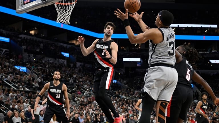 San Antonio Spurs forward Keldon Johnson (3) grabs the rebound...