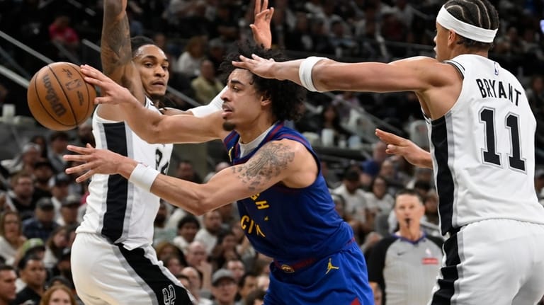Denver Nuggets guard Julian Strawther, center, tangles with San Antonio...