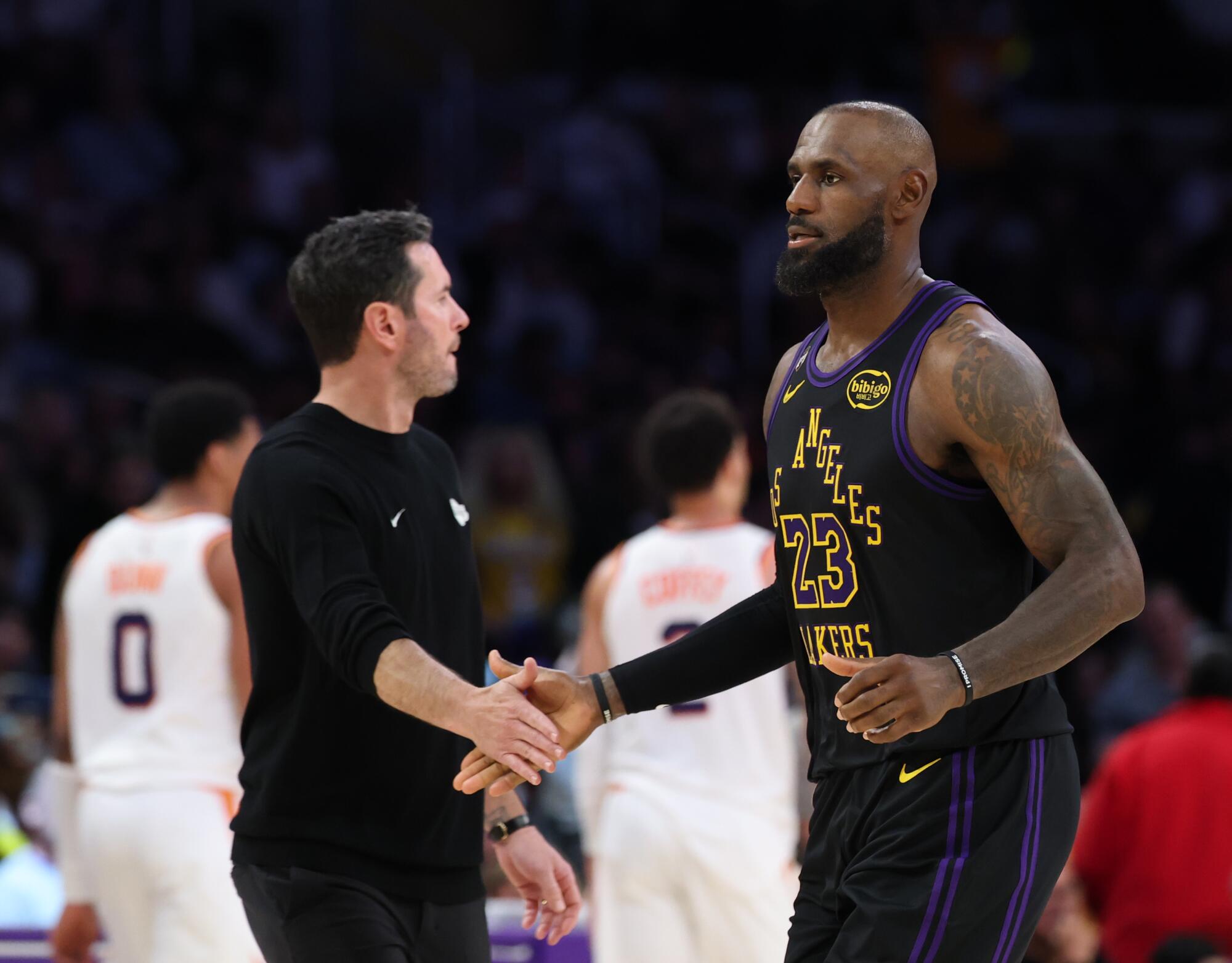 Lakers coach JJ Redick, left, slaps hands with forward LeBron James after he made a shot.