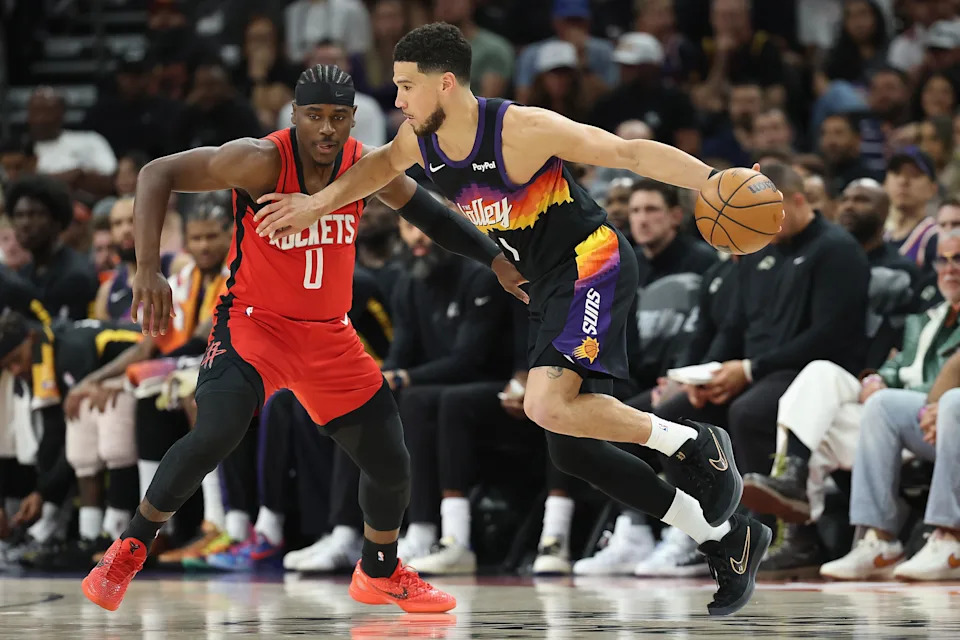 PHOENIX, ARIZONA - APRIL 07: Devin Booker #1 of the Phoenix Suns handles the ball against Aaron Holiday #0 of the Houston Rockets during the second half of the NBA game at Mortgage Matchup Center on April 07, 2026 in Phoenix, Arizona.  NOTE TO USER: User expressly acknowledges and agrees that, by downloading and or using this photograph, user is consenting to the terms and conditions of the Getty Images License Agreement.  (Photo by Christian Petersen/Getty Images)