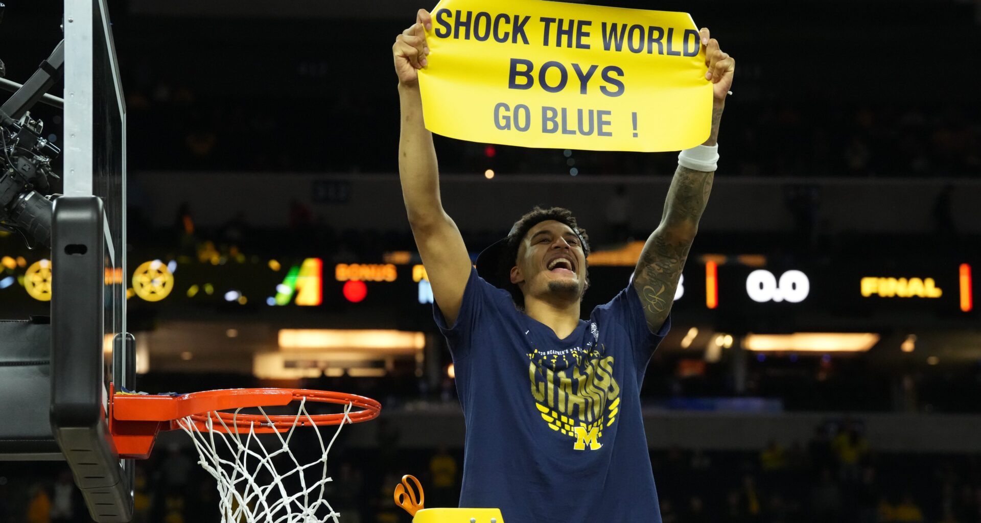 Yaxel Lendeborg holds up a sign and celebrates while cutting down the nets.