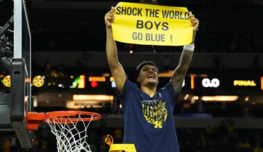 Yaxel Lendeborg holds up a sign and celebrates while cutting down the nets.