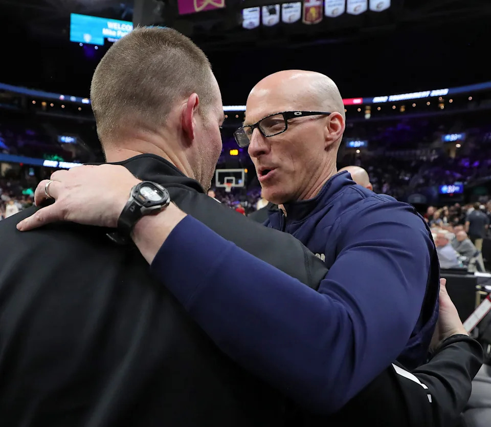 Akron Zips coach John Groce, facing, hugs his brother, Miami RedHawks coach Travis Steele, before the Mid-American Conference Tournament championship game March 15, 2025, in Cleveland, Ohio.