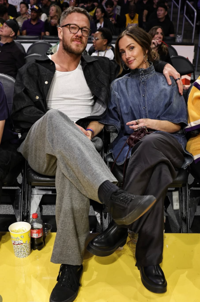 Dan Reynolds of Imagine Dragons (L) sits next to his girlfriend, actress Minka Kelly (R) during Game 5 of the NBA Playoff series between the Houston Rockets and Los Angeles Lakers at Crypto.com Arena. (Photo credit: NBA)