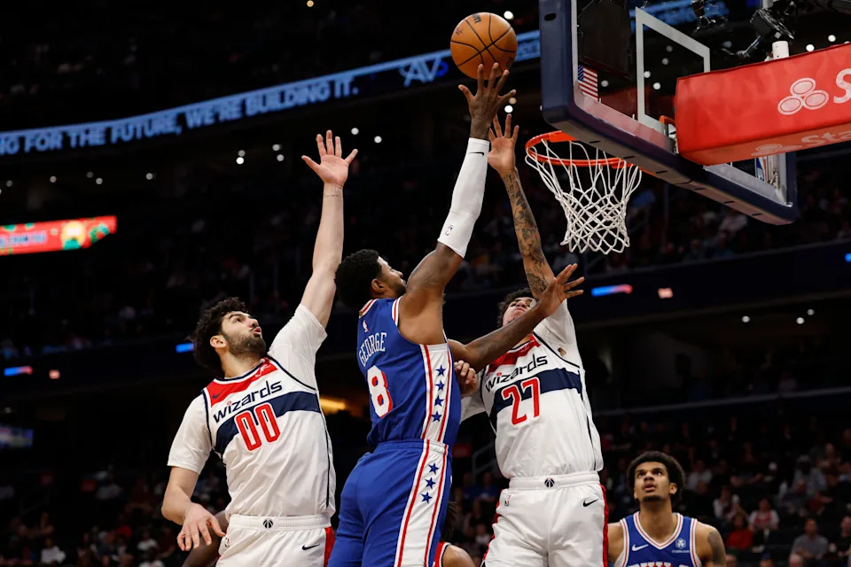 Apr 1, 2026; Washington, District of Columbia, USA; Philadelphia 76ers forward Paul George (8) shoots the ball as Washington Wizards forward Tristan Vukcevic (00) and Wizards guard Will Riley (27) defend in the first halfat Capital One Arena. Mandatory Credit: Geoff Burke-Imagn Images