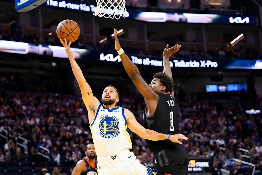 Stephen Curry of the Golden State Warriors lays up a shot against Jae'Sean Tate, #8, of the Houston Rockets.