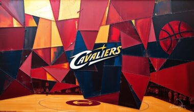 A fragmented, geometric painting depicting a Cleveland Cavaliers basketball game, with sharp planes of red, blue, and gold overlapping to capture the team