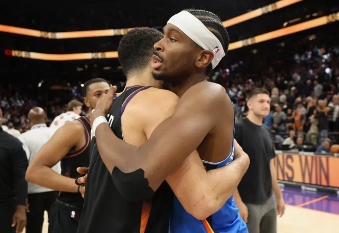 PHOENIX, ARIZONA - JANUARY 04: Shai Gilgeous-Alexander #2 of the Oklahoma City Thunder hugs Devin Booker #1 of the Phoenix Suns following the NBA game at Mortgage Matchup Center on January 04, 2026 in Phoenix, Arizona. The Suns defeated the Thunder 108-105. NOTE TO USER: User expressly acknowledges and agrees that, by downloading and or using this photograph, user is consenting to the terms and conditions of the Getty Images License Agreement. (Photo by Christian Petersen/Getty Images)
