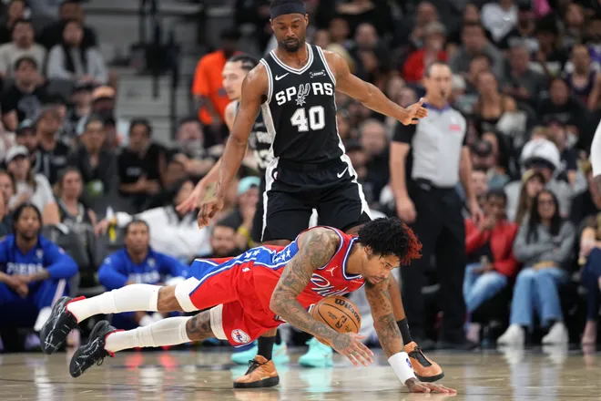 Apr 6, 2026; San Antonio, Texas, USA; Philadelphia 76ers guard Kelly Oubre Jr. (9) falls on a loose ball ahead of San Antonio Spurs forward Harrison Barnes (40) during the first half at Frost Bank Center. Mandatory Credit: Scott Wachter-Imagn Images