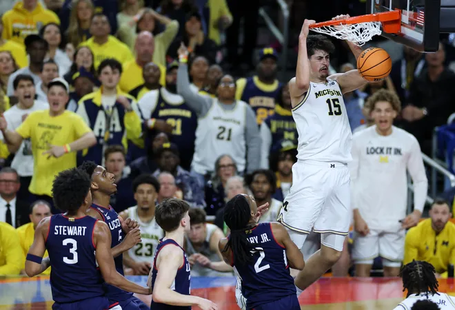 Apr 6, 2026; Indianapolis, IN, USA; Michigan Wolverines center Aday Mara (15) dunks the ball past UConn Huskies guard Silas Demary Jr. (2) in the second half during the national championship of the Final Four of the men's 2026 NCAA Tournament at Lucas Oil Stadium. Mandatory Credit: Trevor Ruszkowski-Imagn Images