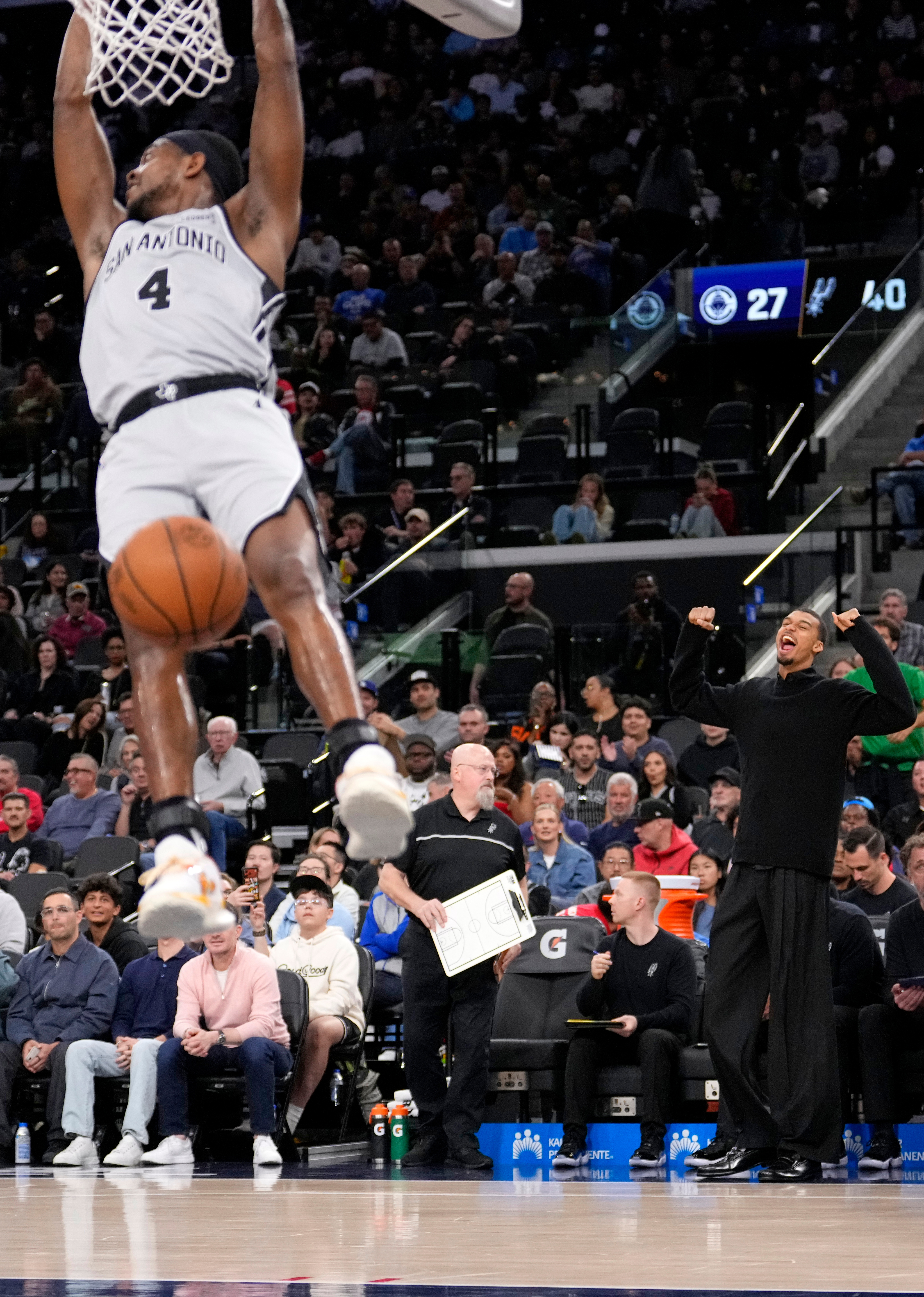 San Antonio Spurs guard De’Aaron Fox, left, hangs from the...