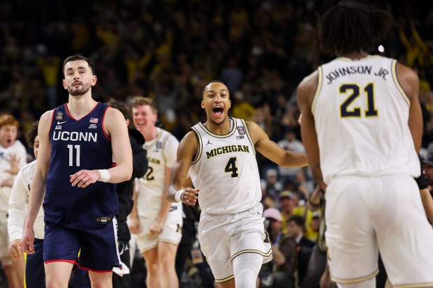 Michigan guard Nimari Burnett (4) and Michigan forward Morez Johnson Jr. (21) celebrate after defeating UConn, 69-63, in the NCAA title game on April 6, 2026, at Lucas Oil Stadium in Indianapolis. (Armando L. Sanchez/Chicago Tribune)