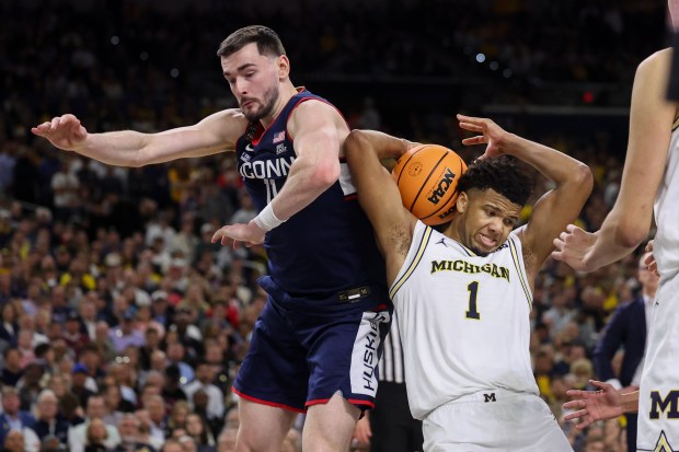 UConn forward Alex Karaban (11) and Michigan guard Trey McKenney (1) try to grab a loose ball during the second half of the NCAA title game between UConn and Michigan April 6, 2026, at Lucas Oil Stadium in Indianapolis. (Armando L. Sanchez/Chicago Tribune)