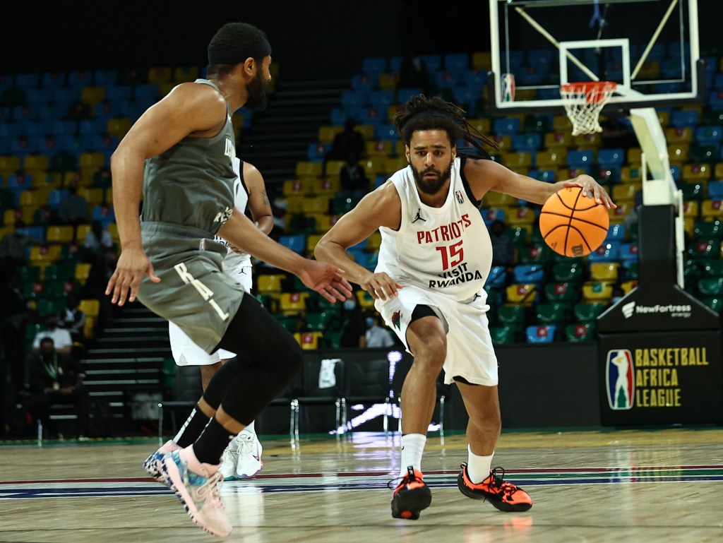 J. Cole dribbling the ball against another player during a basketball game.