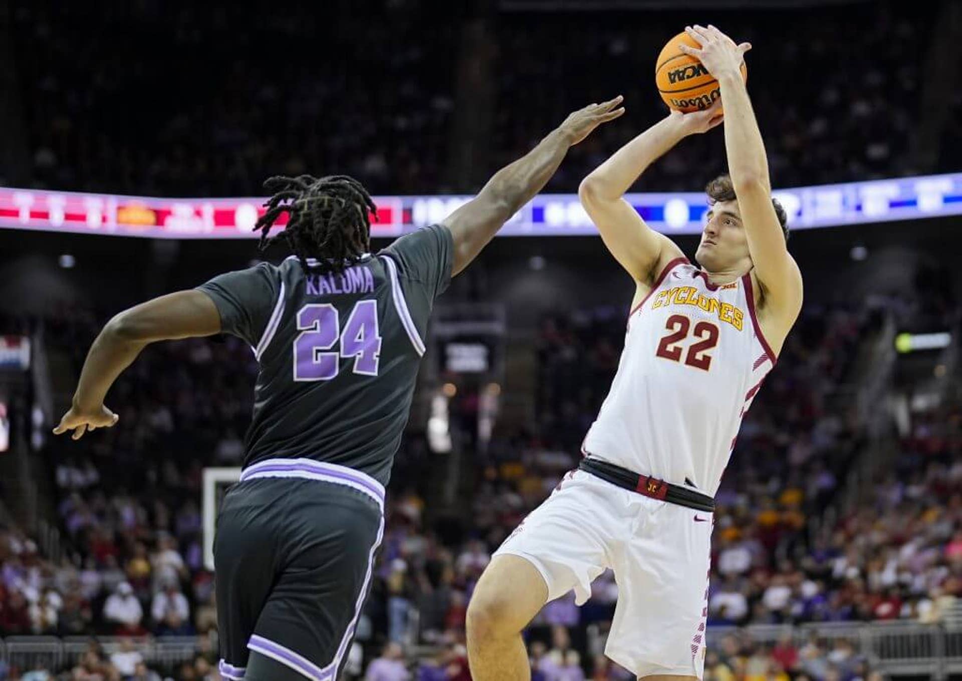 Iowa State player Milan Momcilovic rises to release a fadeaway jump shot over the outstretched arm of a Kansas State defender.
