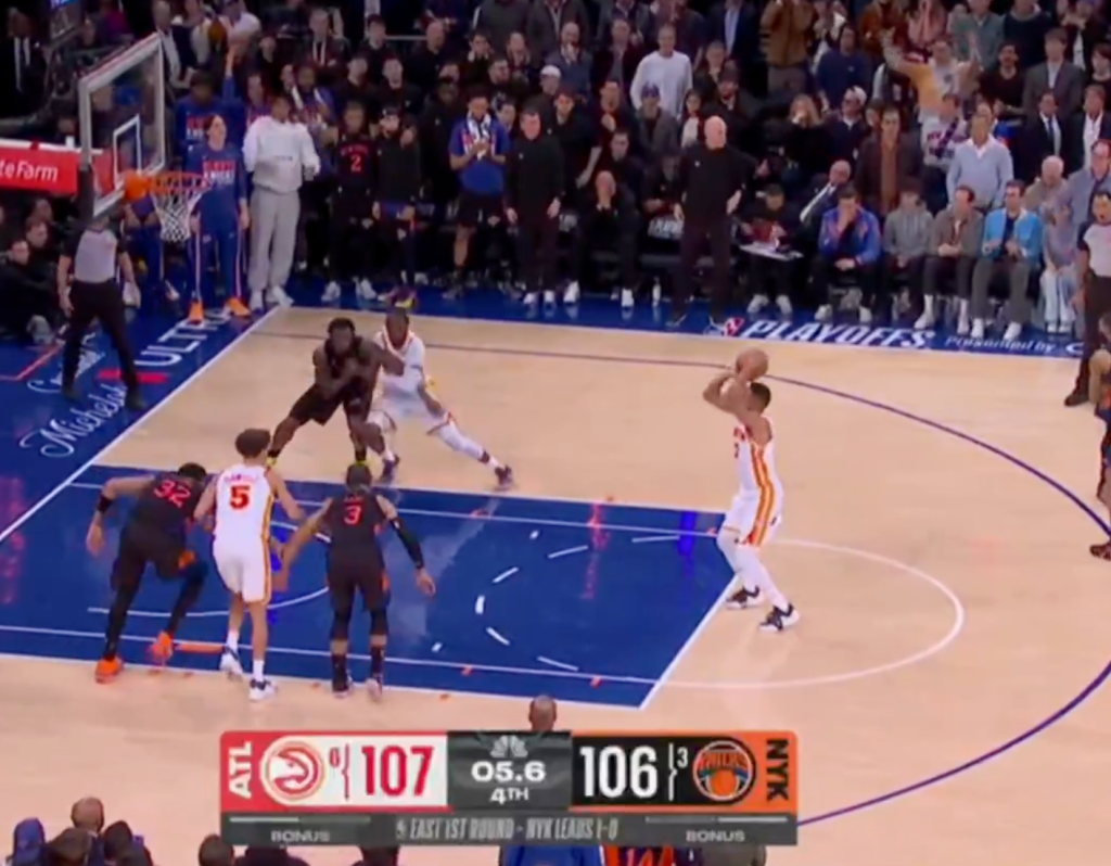 A basketball player in a white and orange uniform shoots a jump shot with 5.6 seconds left in the 4th quarter, Hawks leading Knicks 107-106.