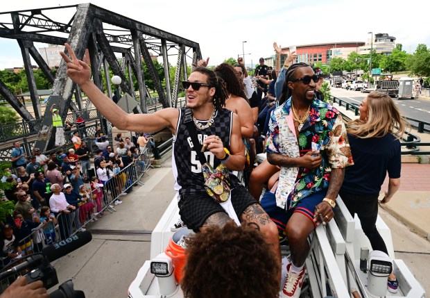 Denver Nuggets players Aaron Gordon, left, and Kentavious Caldwell-Pope, sit on the ladder of a Denver Fire Department fire engine and wave to fans as they take part in the parade for the NBA champions in Denver, Colorado on June 15, 2023. The Denver Nuggets defeated the Miami Heat in five games to with their first ever NBA championship. Players, coaches and their families rode fire engines from Ball Arena, past Union Station up 17th Street to Broadway and to the Civic Center where a rally was held in their honor. (Photo by Helen H. Richardson/The Denver Post)