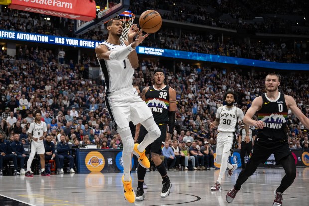 Victor Wembanyama (1) of the San Antonio Spurs keeps the ball inbounds by passing to teammate Devin Vassell (24) during overtime of a 136-134 Nuggets win on Saturday, April 4, 2026, at Ball Arena in Denver. (Photo by Timothy Hurst/The Denver Post)