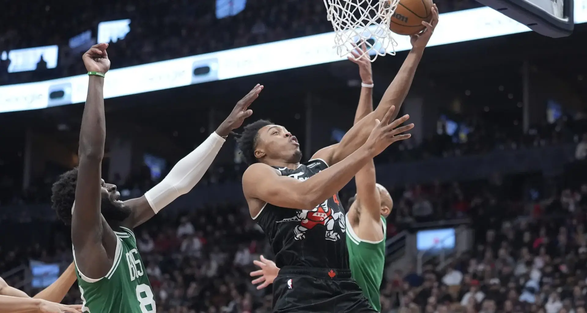 Dec 7, 2025; Toronto, Ontario, CAN; Toronto Raptors guard Scottie Barnes (4) goes up to make a basket against Boston Celtics center Neemias Queta (88) and guard Derrick White (9) during the second half at Scotiabank Arena. Mandatory Credit: John E. Sokolowski-Imagn Images