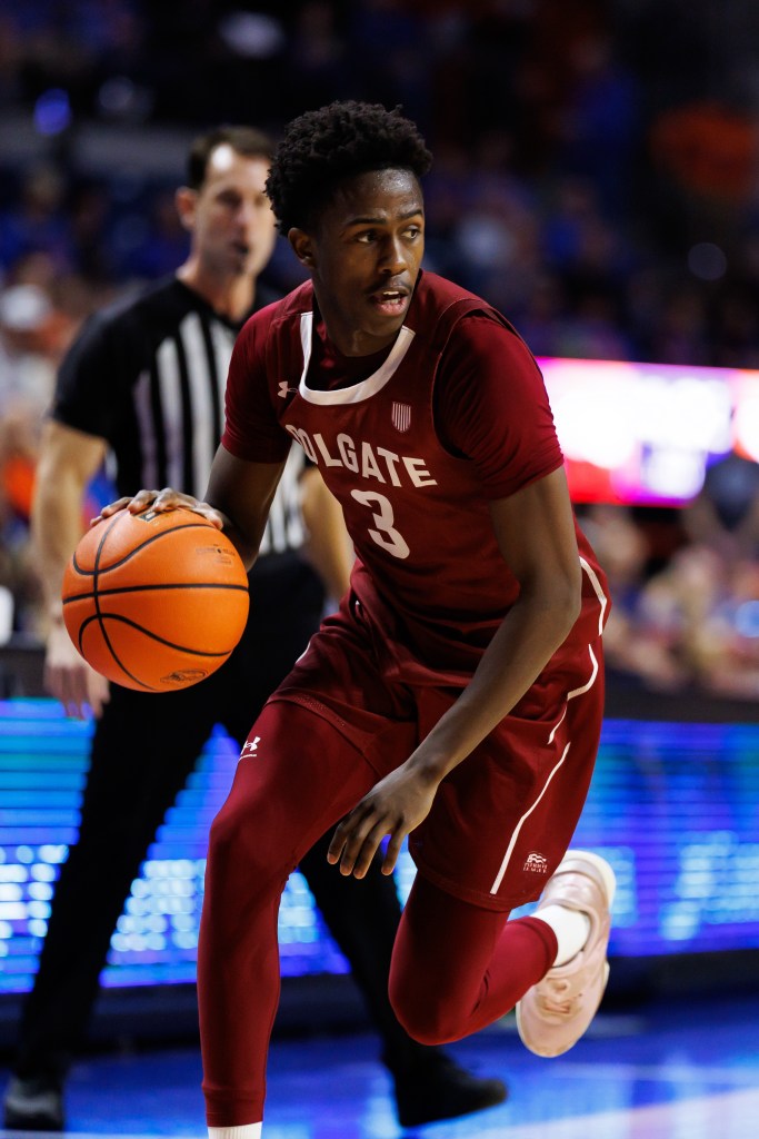 A basketball player in a maroon jersey with "COLGATE 3" written on it dribbles a basketball.