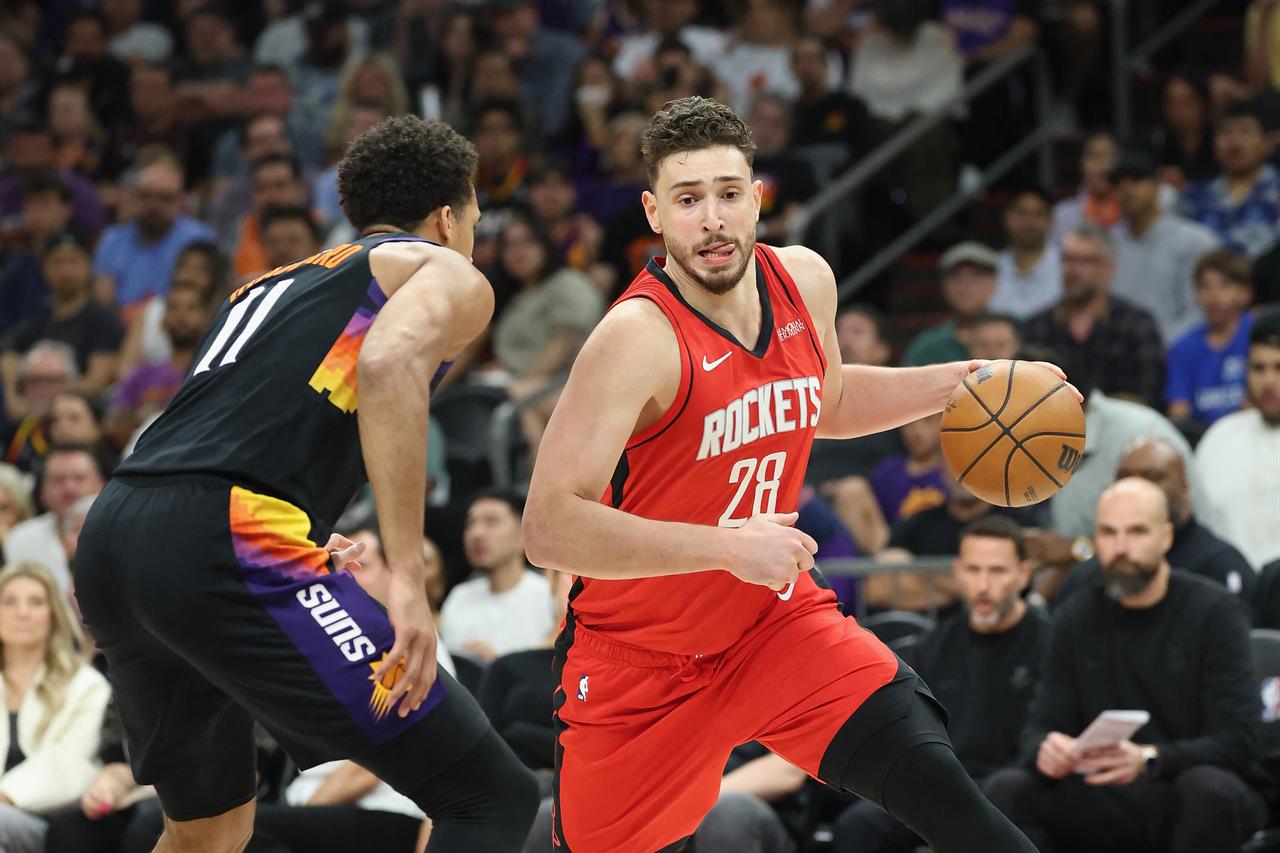 Alperen Sengun (#28) of the Houston Rockets dribbles past Oso Ighodaro (#11) of the Phoenix Suns in the second half at Mortgage Matchup Center in Phoenix, Arizona, April 7, 2026. (AFP Photo)