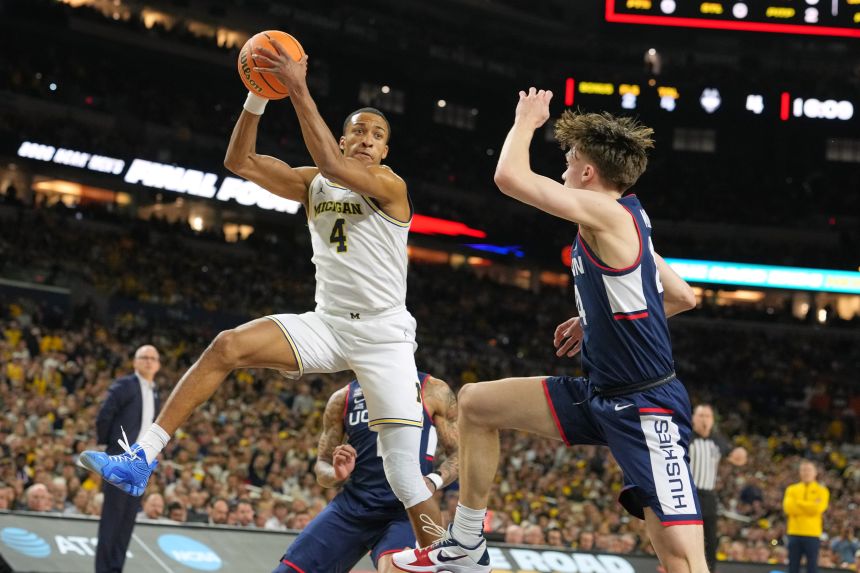 Michigan's Nimari Burnett looks to pass around UConn's Braylon Mullins.