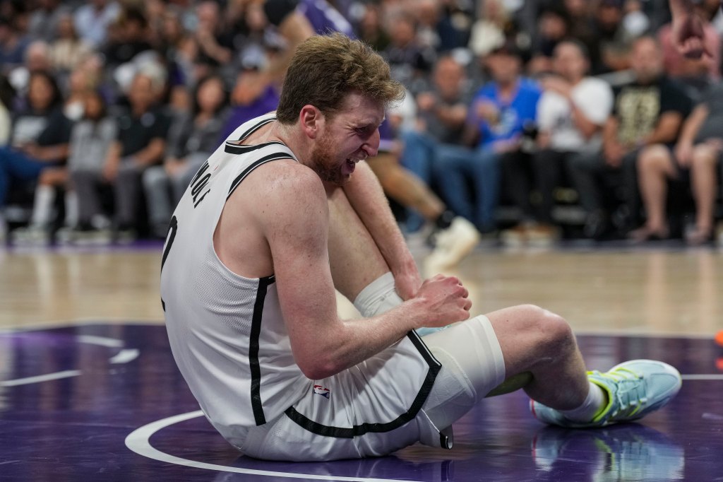 Brooklyn Nets forward Danny Wolf grabs his ankle in pain on the court.